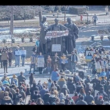 Aerial photo of the Alma Mater statue with a crowd of people holding signs to support Ukraine and wearing blue and yellow.